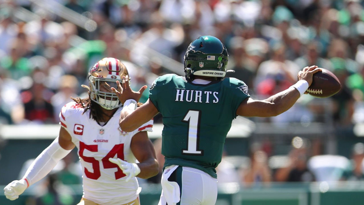 Fred Warner, LB de los 49ers (izquierda), Jalen Hurts, QB de los Eagles (centro)